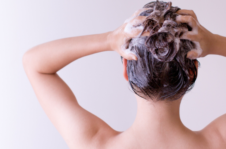 femme massant sa tête avec du shampoing sur les cheveux