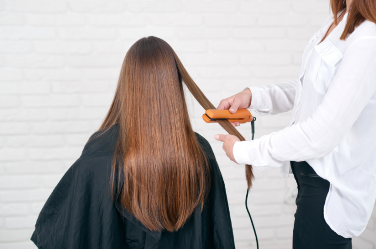 coiffeuse lissant les cheveux d'une femme