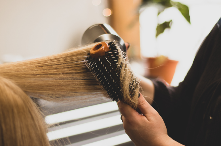 coiffeuse réalisant un brushing sur une femme dans un salon de coiffure