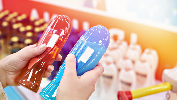 femme comparant deux shampoings bleus en magasin