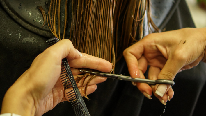 coiffeuse coupant les pointes de cheveux d'une cliente