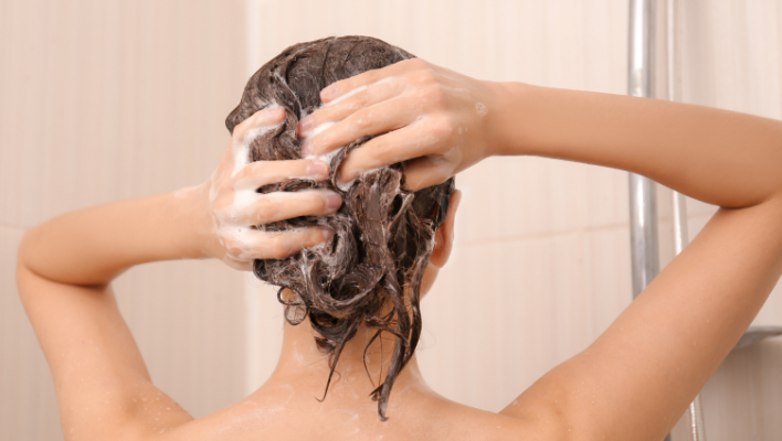 femme massant ses cheveux sous la douche