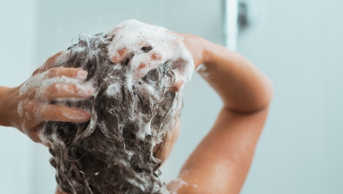 femme appliquant du shampoing sur ses cheveux