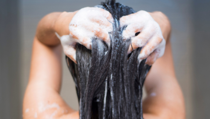 femme se lavant les cheveux avec du gel douche